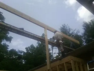 Carpenter setting a ridge beam over a new addition frame — Ice Dam Removal by Roofing Brothers in Bear Creek