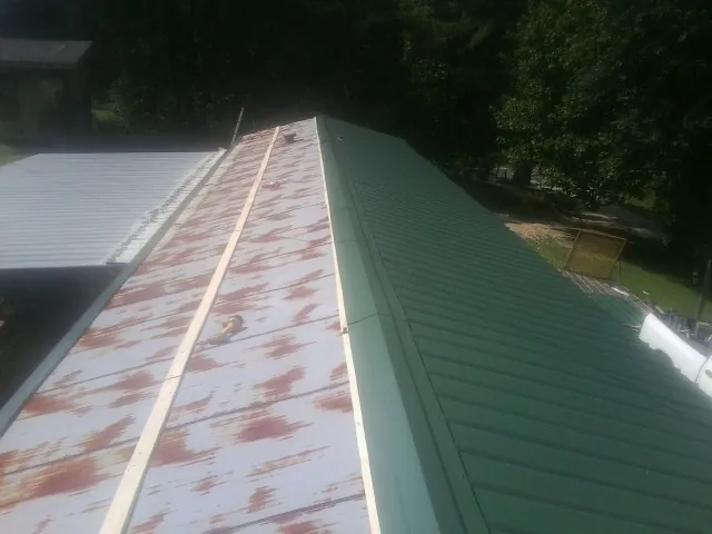 Old rusted panels beside newly installed green metal roofing — Wind Damage Roof Repair by Roofing Brothers in Bear Creek