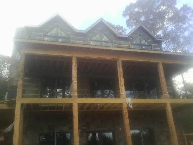 Dormers and porch framing on a large log home under construction — Roof Coating work by our crew in Bear Creek