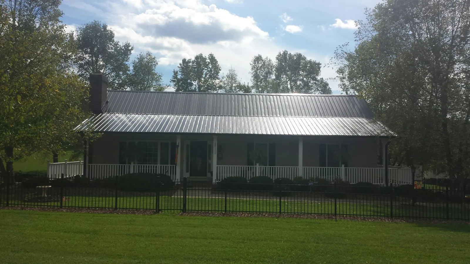 Gray metal roof on a brick ranch with a full width front porch — Gutter Guard Installation work by our crew in Bear Creek
