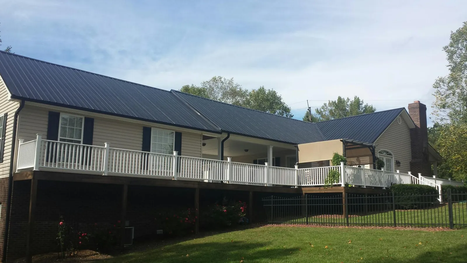 Black metal roof above a long white railed deck on a hillside home in Bear Creek